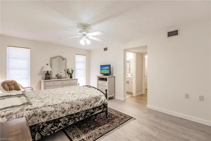 Bedroom featuring ceiling fan, light hardwood / wood-style floors, connected bathroom, and multiple windows