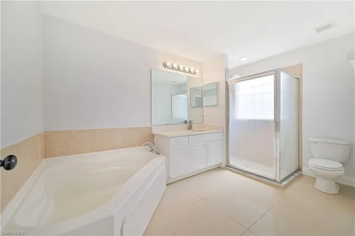 Full bathroom featuring tile floors, oversized vanity, toilet, and separate shower and tub