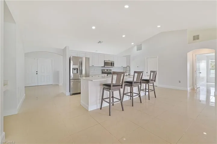Kitchen featuring stainless steel appliances, a kitchen island with sink, and light tile floors