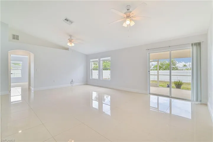 Spare room featuring vaulted ceiling, ceiling fan, and light tile floors