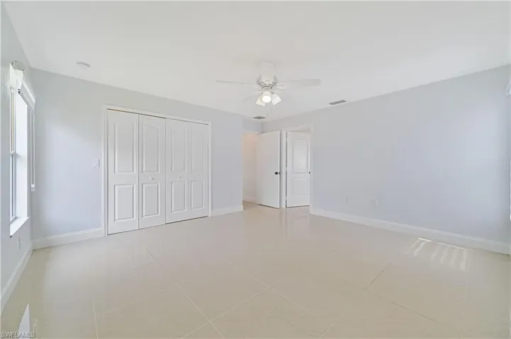 Unfurnished bedroom with ceiling fan, a closet, and light tile floors