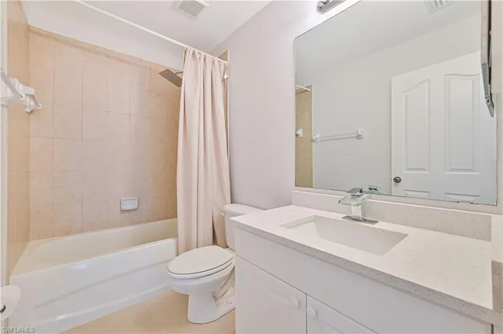 Full bathroom with tile floors, shower / bath combo, oversized vanity, and toilet