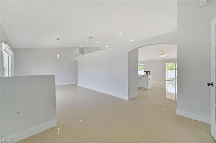 Tiled empty room featuring vaulted ceiling and ceiling fan