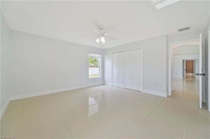 Unfurnished bedroom featuring a closet, ceiling fan, and light tile floors