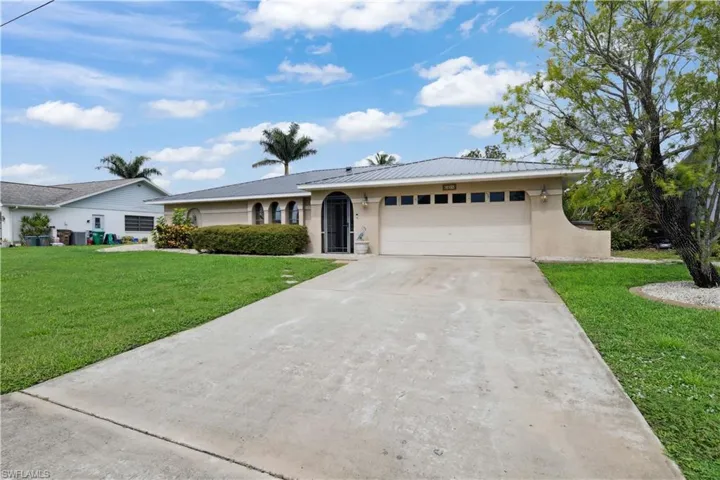 Ranch-style home with stucco siding, an attached garage, driveway, and a front yard