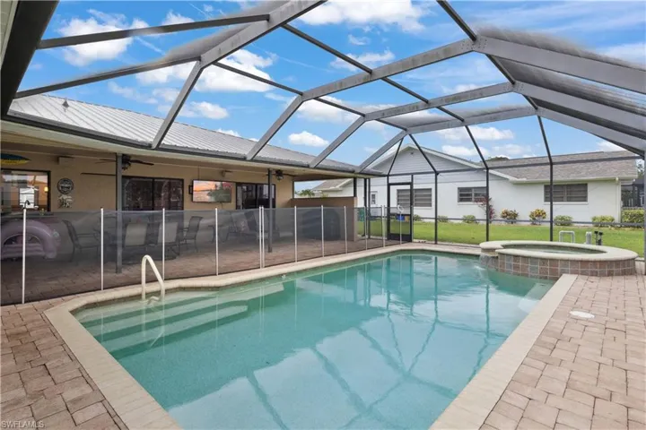 View of pool featuring ceiling fan, a patio area, a pool with connected hot tub, and glass enclosure