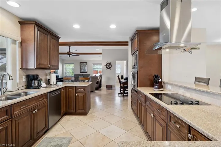 Kitchen with appliances with stainless steel finishes, island exhaust hood, a ceiling fan, a peninsula, and light tile patterned floors