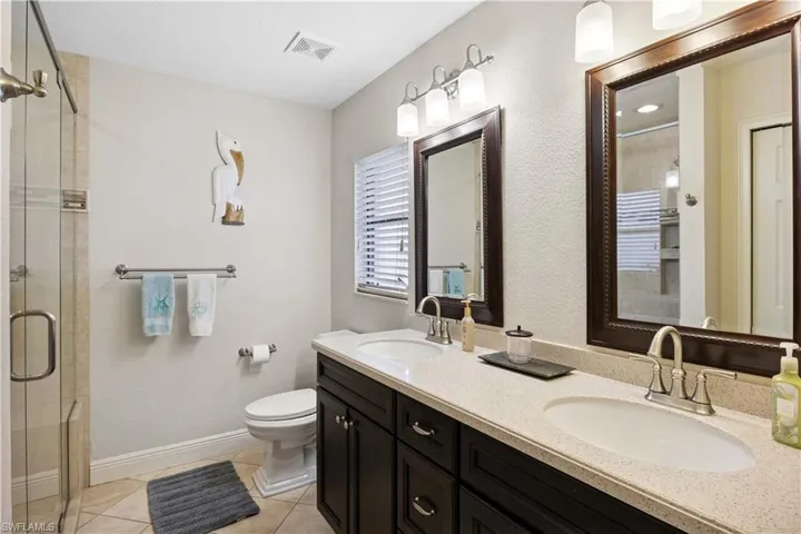 Bathroom featuring double vanity, a shower stall, and tile patterned flooring