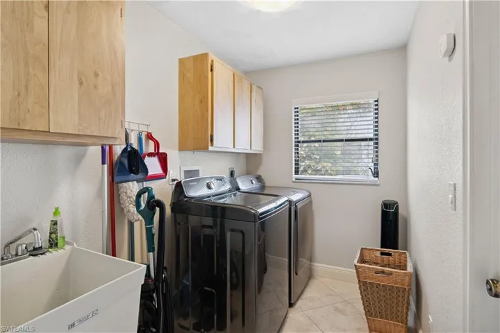 Laundry area with cabinet space, independent washer and dryer, and light tile patterned flooring