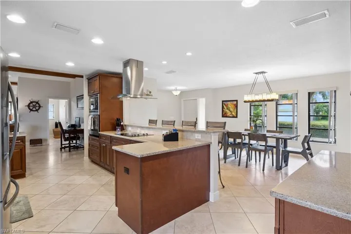 Kitchen featuring extractor fan, appliances with stainless steel finishes, a peninsula, light tile patterned flooring, and recessed lighting