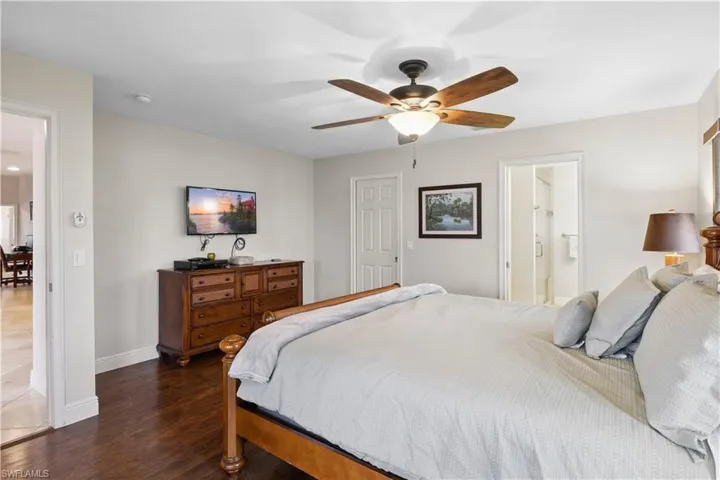 Bedroom with wood finished floors, ceiling fan, and ensuite bathroom