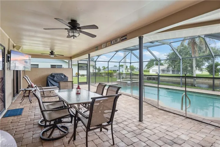 View of patio / terrace featuring ceiling fan, a pool with connected hot tub, a water view, and a lanai