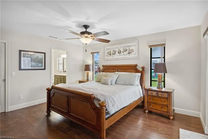 Bedroom with multiple windows, dark wood finished floors, and connected bathroom