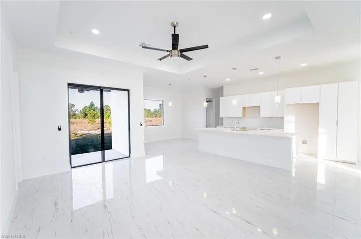 Unfurnished living room with ceiling fan, a tray ceiling, and sink