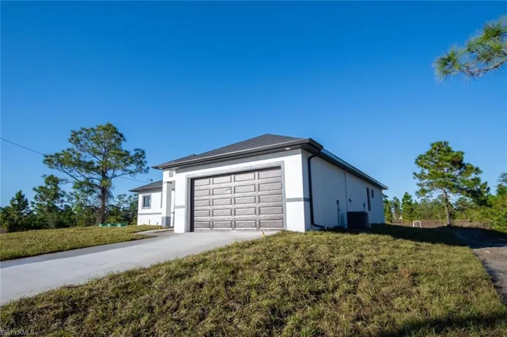View of property exterior with cooling unit, a garage, and a yard