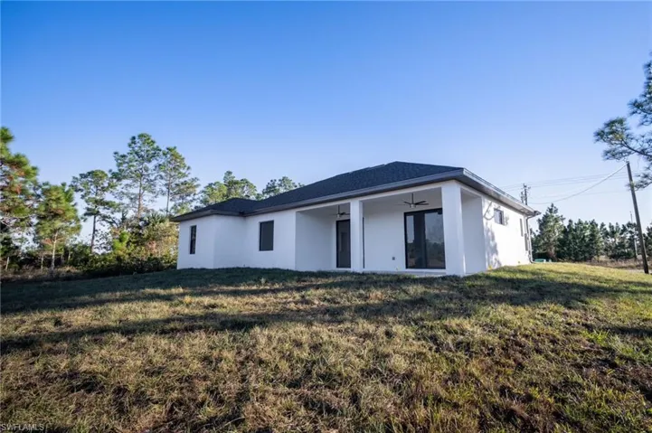 Rear view of property with ceiling fan and a lawn