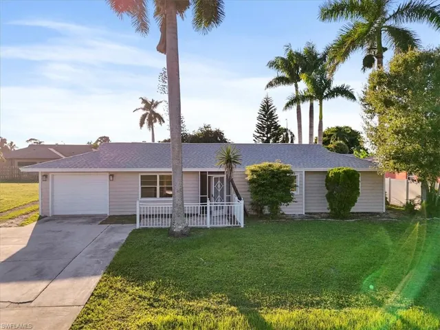 Ranch-style home with a front lawn, driveway, an attached garage, and covered porch