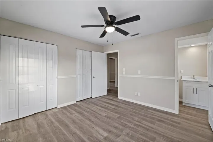Unfurnished bedroom with two closets, light wood finished floors, a ceiling fan, and connected bathroom