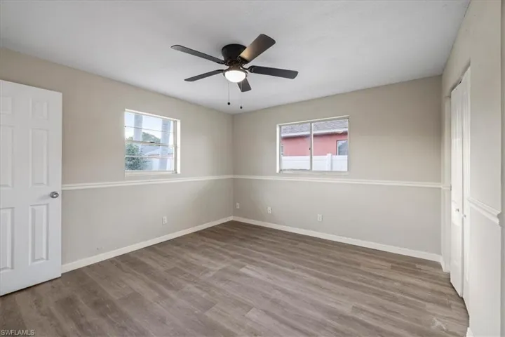 Unfurnished bedroom with a closet, wood finished floors, multiple windows, and ceiling fan
