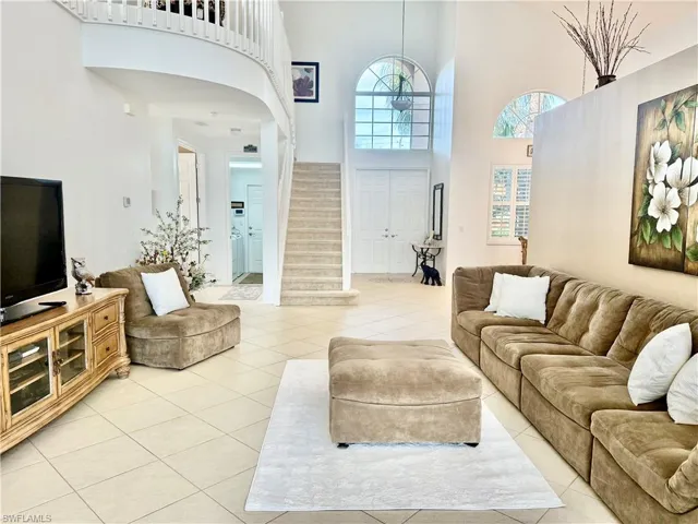 Living area with a high ceiling, tile patterned flooring, and stairway
