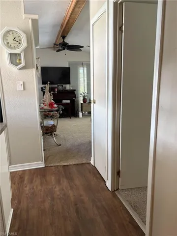 Hallway with beamed ceiling and dark wood-type flooring