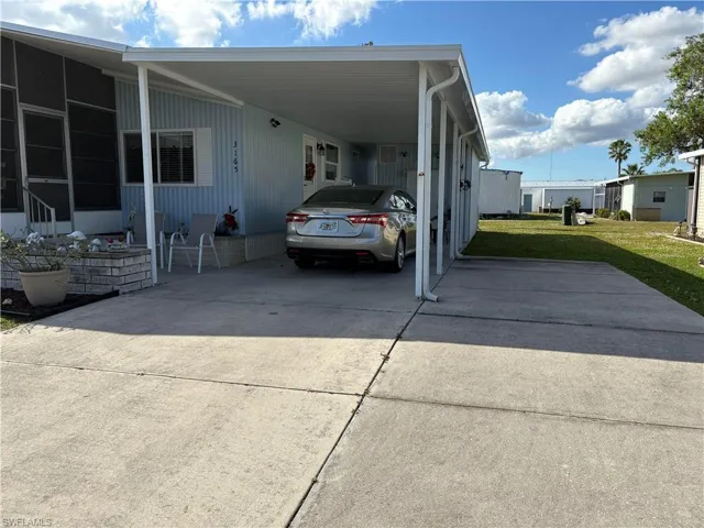 View of side of property with a carport and a yard