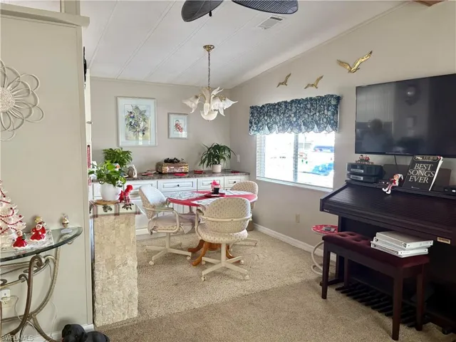 Carpeted dining room with a notable chandelier and vaulted ceiling
