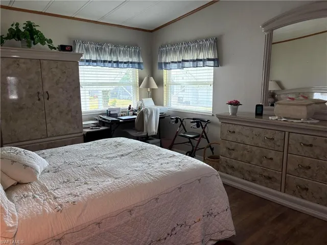 Bedroom with dark hardwood / wood-style flooring, vaulted ceiling, and ornamental molding