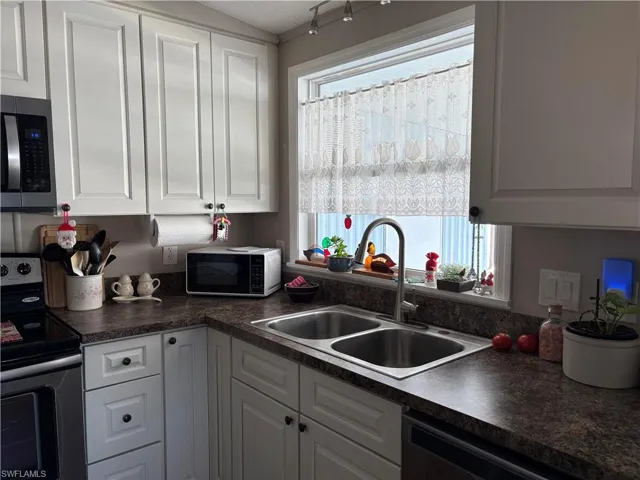 Kitchen featuring white cabinets, sink, and appliances with stainless steel finishes