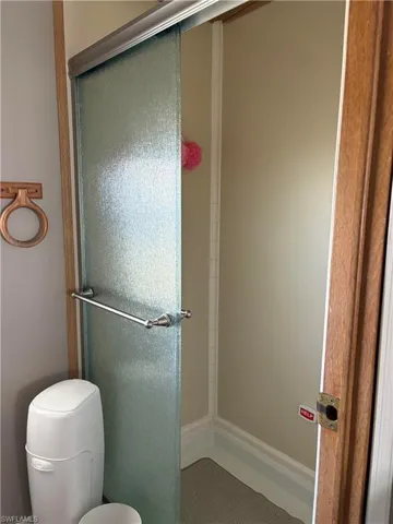 Bathroom featuring toilet and a shower with shower door