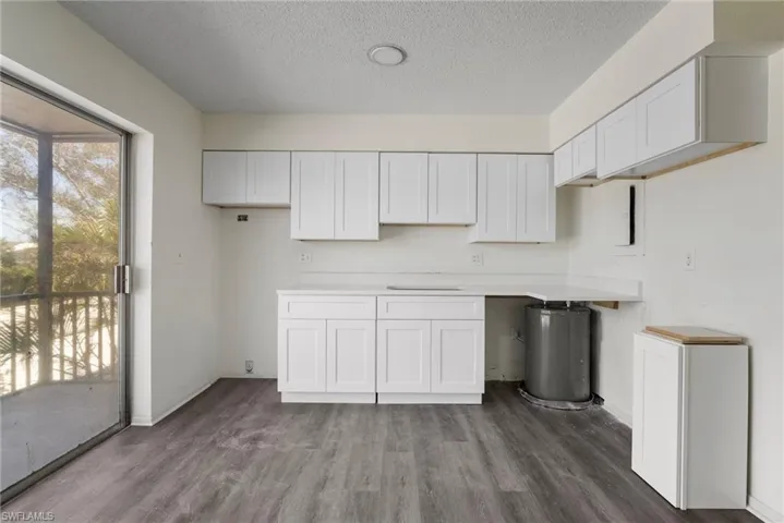Kitchen featuring hardwood / wood-style flooring, a textured ceiling, and white cabinets