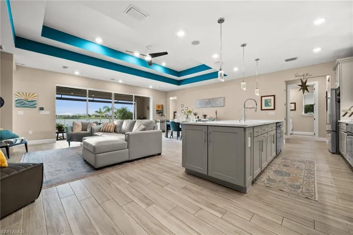 Kitchen with gray cabinets, open floor plan, light countertops, a tray ceiling, and recessed lighting