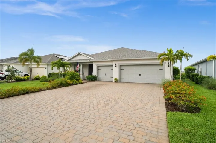 Single story home featuring decorative driveway, a garage, stucco siding, a front lawn, and roof with shingles