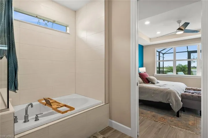 Ensuite bathroom featuring wood-look tile floors and a relaxing tiled tub