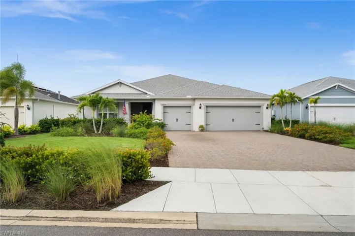 Single story home with driveway, an attached garage, roof with shingles, stucco siding, and a front yard