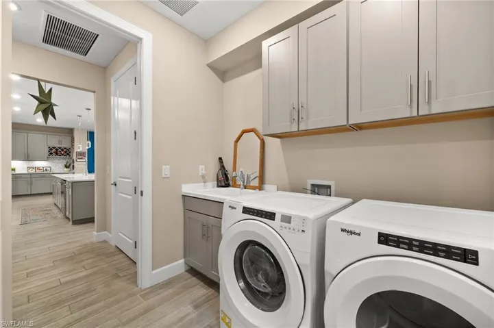 Laundry area featuring washer and clothes dryer, light wood-look tile floors, and cabinet space