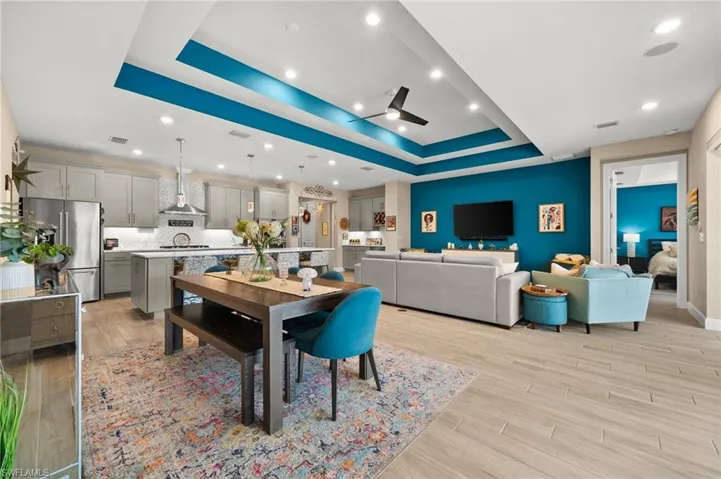 Dining space featuring a tray ceiling, light wood finished floors, a ceiling fan, and recessed lighting