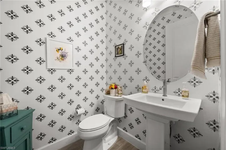 Bathroom featuring wood-look tile floors and wallpapered walls