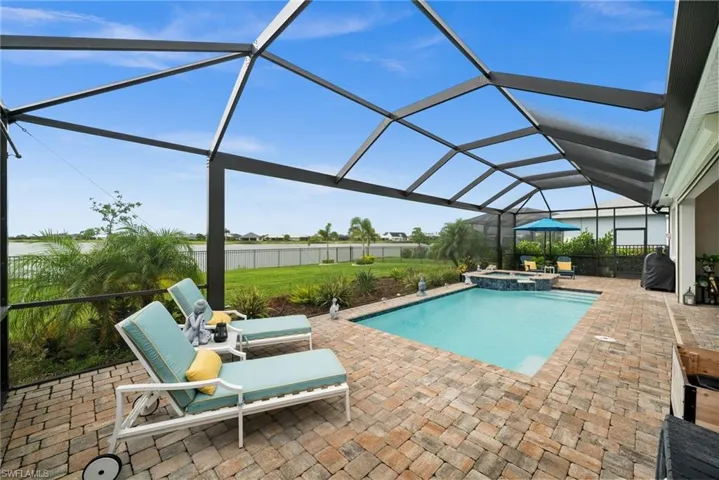 View of swimming pool with a patio, a pool with connected hot tub, and glass enclosure
