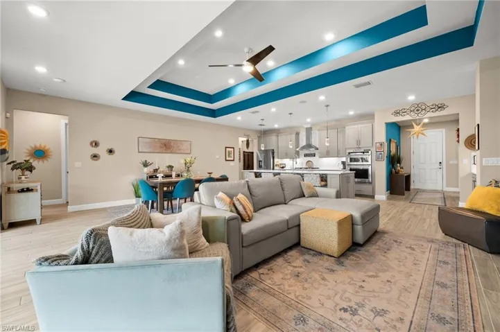 Living area featuring a tray ceiling, ceiling fan, recessed lighting, and light wood-style  tile floors