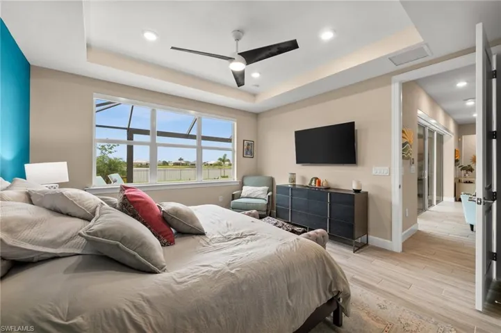 Bedroom with a tray ceiling, light wood-style floors, recessed lighting, and a ceiling fan