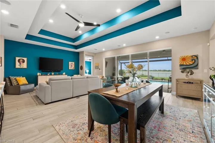 Dining room featuring a tray ceiling, a ceiling fan, light wood-look tile flooring, and recessed lighting