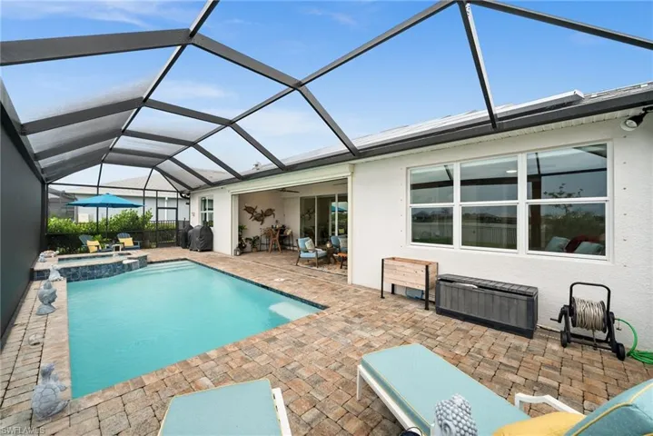 View of swimming pool with a patio area, a pool with connected hot tub, glass enclosure, and ceiling fan