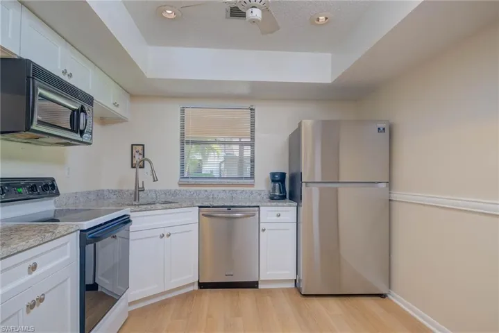Kitchen featuring white cabinetry, stainless steel appliances, a raised ceiling, and sink