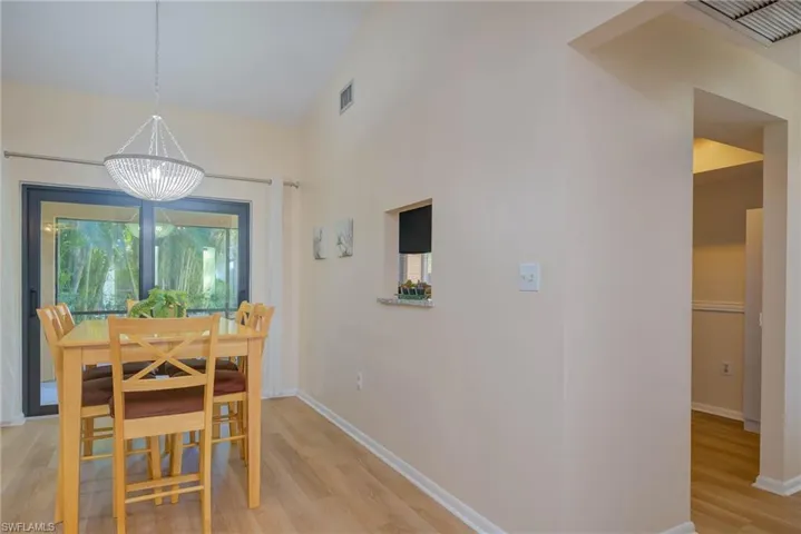Dining room featuring vaulted ceiling, an inviting chandelier, and light hardwood / wood-style flooring