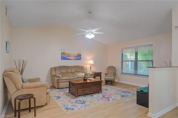 Living room with ceiling fan, lofted ceiling, and light hardwood / wood-style floors