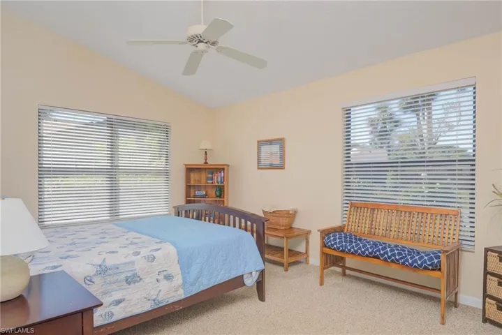 Bedroom featuring ceiling fan, vaulted ceiling, and light carpet