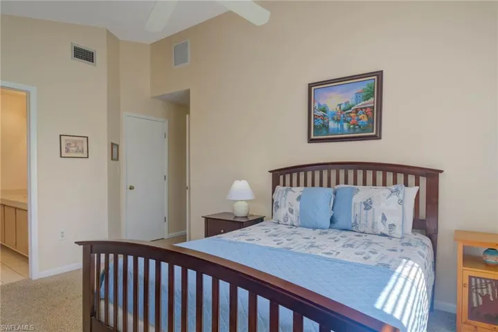 Bedroom with ceiling fan, light carpet, and a high ceiling