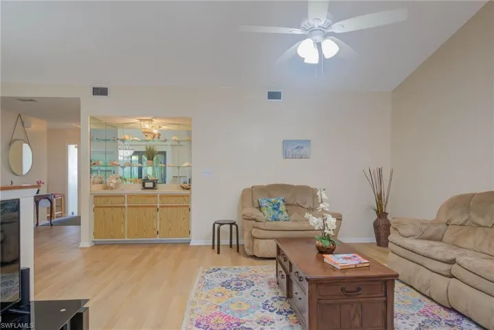 Living room featuring ceiling fan with notable chandelier and light hardwood / wood-style flooring