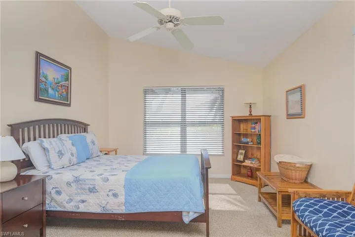 Bedroom with ceiling fan, vaulted ceiling, and light carpet